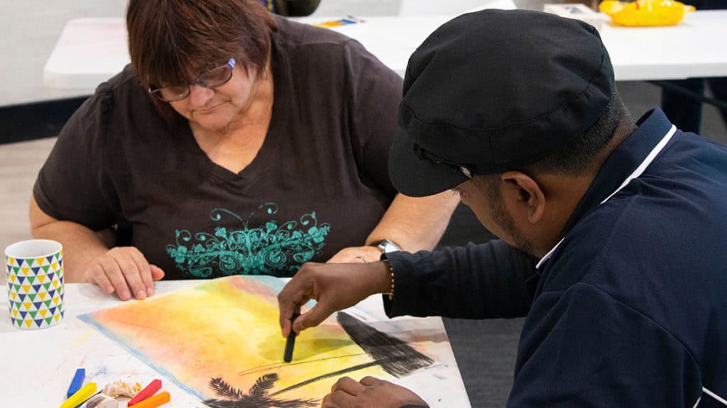 NDIS caregiver and client collaborating on an art activity, showcasing compassionate home care and disability support in Australia.