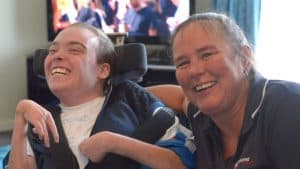 Empathetic caregiver providing support and companionship to a young man with a disability, highlighting personalised care services.