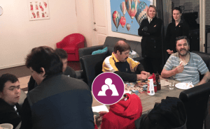 Adults and children sharing a hot meal in a warm indoor setting, representing NDIS community support and inclusive disability care services.